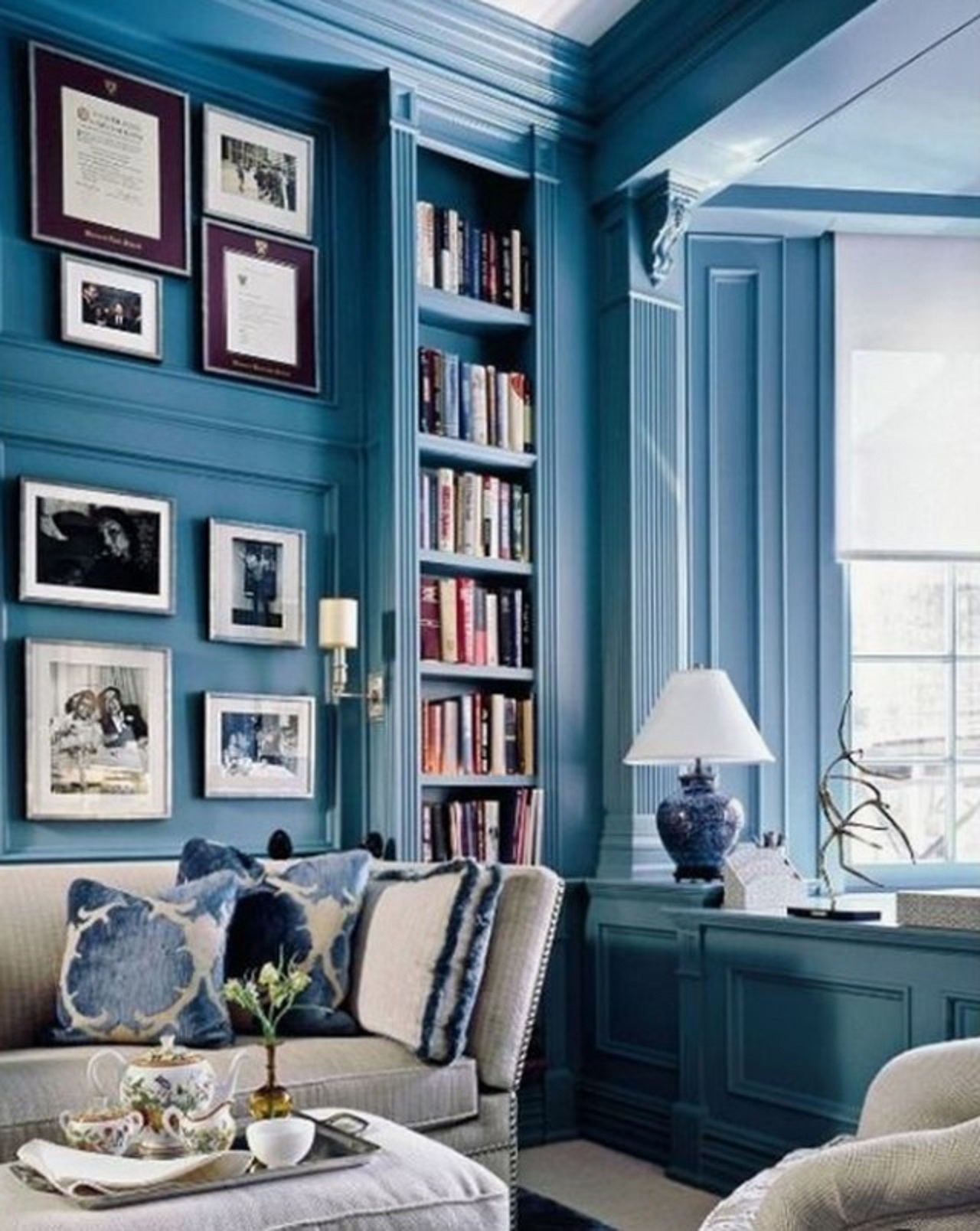 Một văn phòng và thư viện tại nhà màu xanh tươi sáng với giá sách tích hợp và đồ nội thất và tác phẩm nghệ thuật màu trắng thanh lịch.