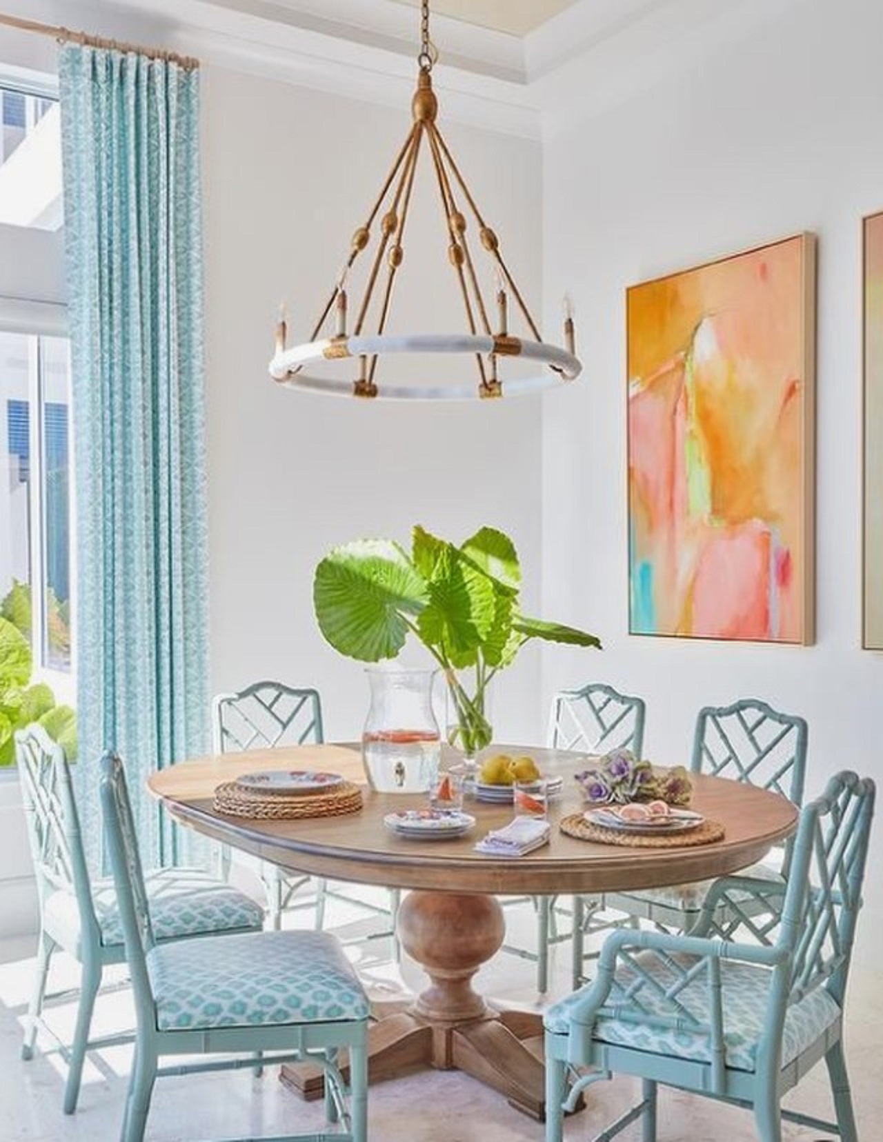 Không gian ăn uống màu trắng được tô điểm màu sắc bằng cách sử dụng rèm cửa màu xanh và các tác phẩm nghệ thuật rực rỡ trên tường