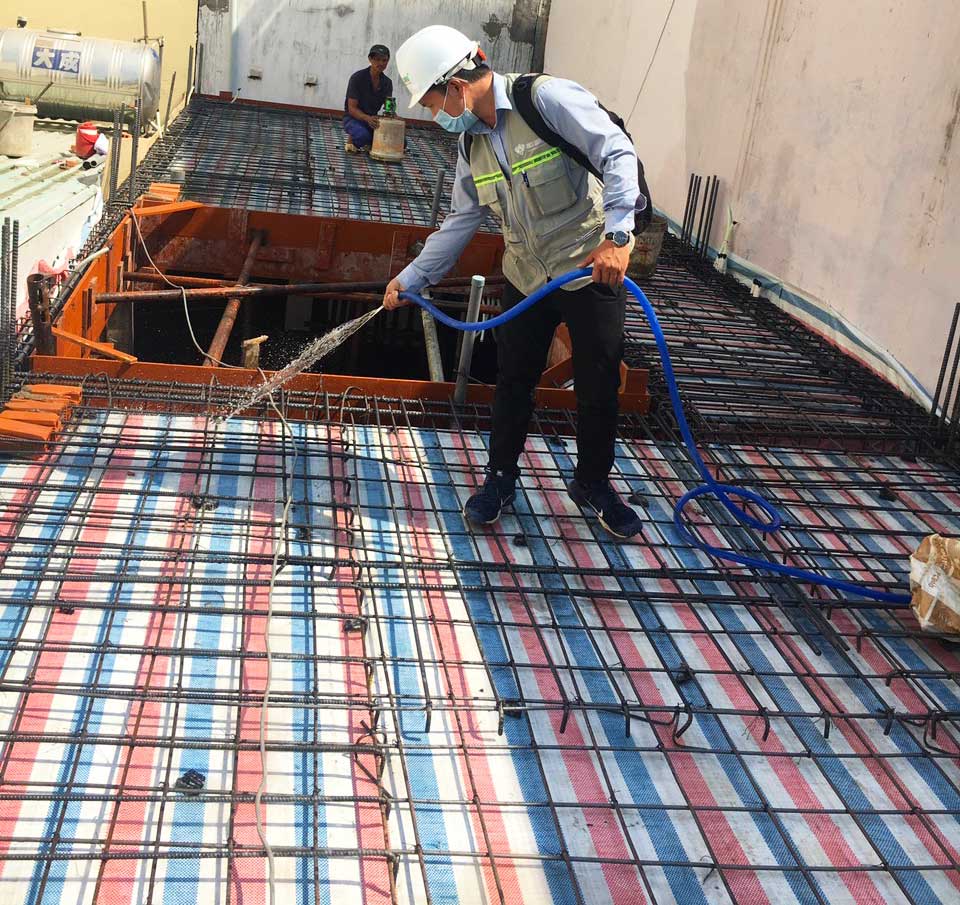 Kỹ sư Việt Quang đang dùng lưới để rửa sạch bụi trên thép sàn trước khi đổ bê tông