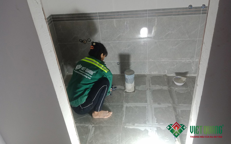 Công nhân vệ sinh gạch và chà ron gạch trong nhà vệ sinh