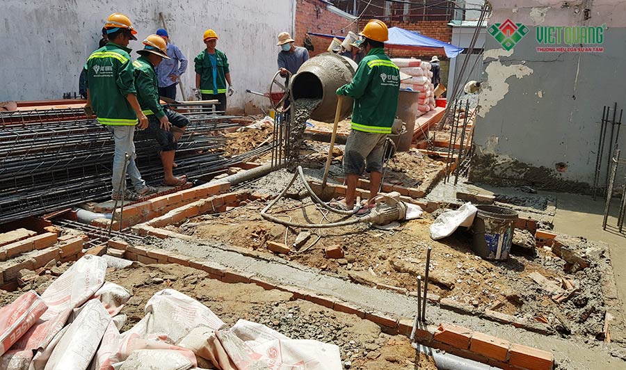 Công nhân Việt Quang đang thi công đổ bê tông móng bằng máy trộn tại công trình