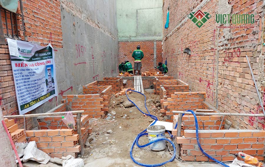 Công nhân Việt Quang đang tiến hành thi công xây tường bao móng đài cọc công trình nhà chọ Hiền quận Bình Tân