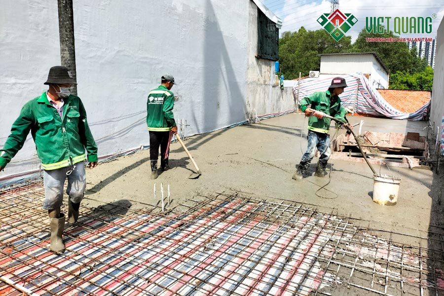 Công nhân Việt Quang đang đổ bê tông tươi sàn lầu 1 và sử dụng đầm dùi trong quá trình đổ bê tông