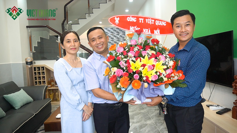 Giám đốc chi nhánh Tân Bình Ông. Lê Quang Tự (bên trái) tặng hoa chúc mừng tân gia vợ chồng anh Lực quận 12.